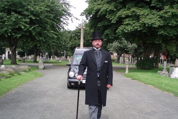 funeral-director-walks-in-front-of-hearse